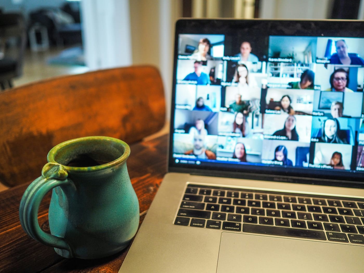 Coffee mug on desk next to laptop displaying Zoom meeting.